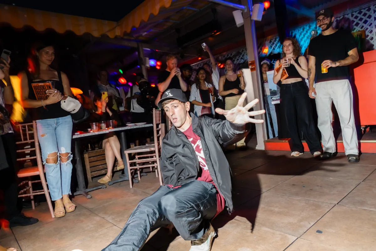 Breakdancer performing on dance floor surrounded by cheering crowd at party.