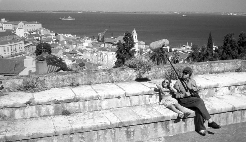 a man holding a boom mic, sitting on stone steps with a child