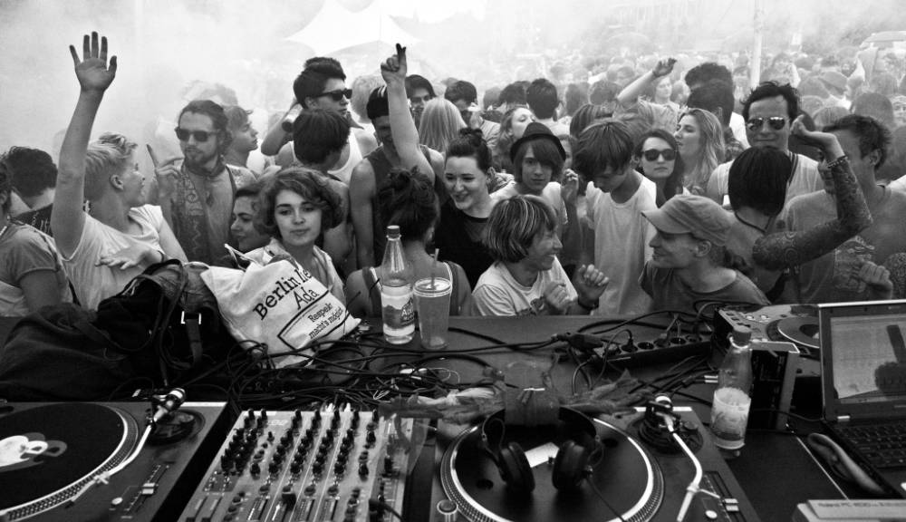 party-goers dancing in front of DJ booth