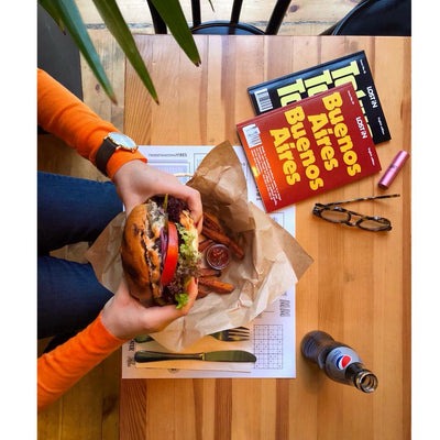 person eating a burger and reading LOST iN guide books