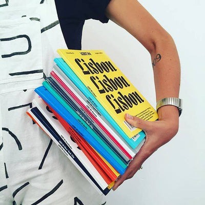 woman holding stack of LOST iN guide books