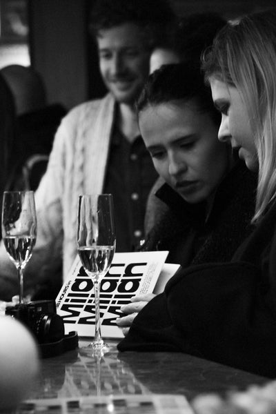 two women at bar, reading LOST iN Milan guide book